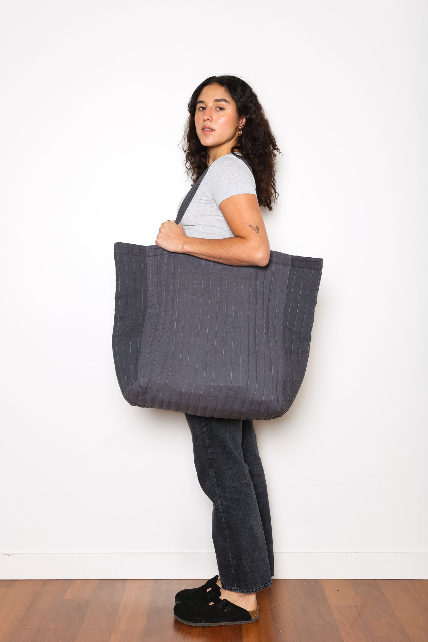 Model showing side shot of Charcoal ESME oversized quilted tote - photographed on a white background