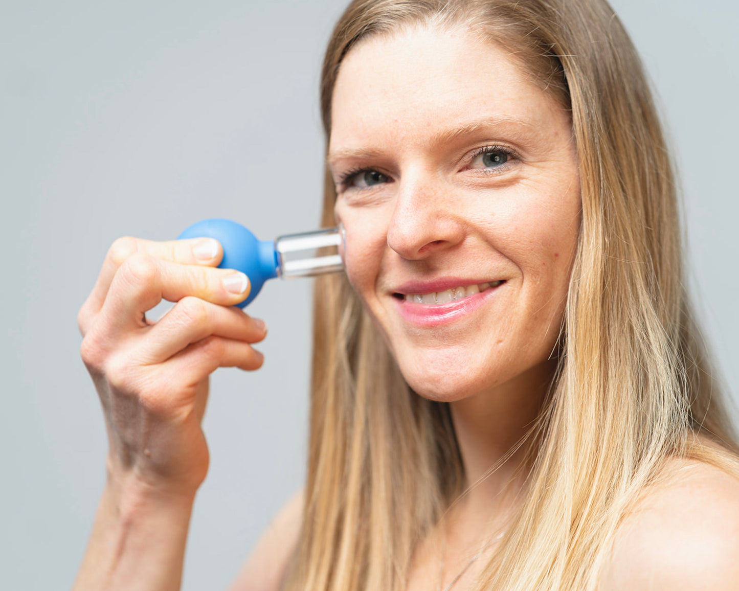 Close up of a woman using a blue glass facial cup
