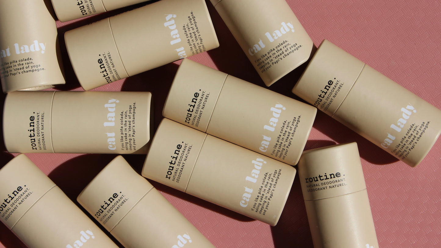 A display of many Cat Lady - Natural Deodorant sticks from Routine, beige deodorant stick on a dusty pink background