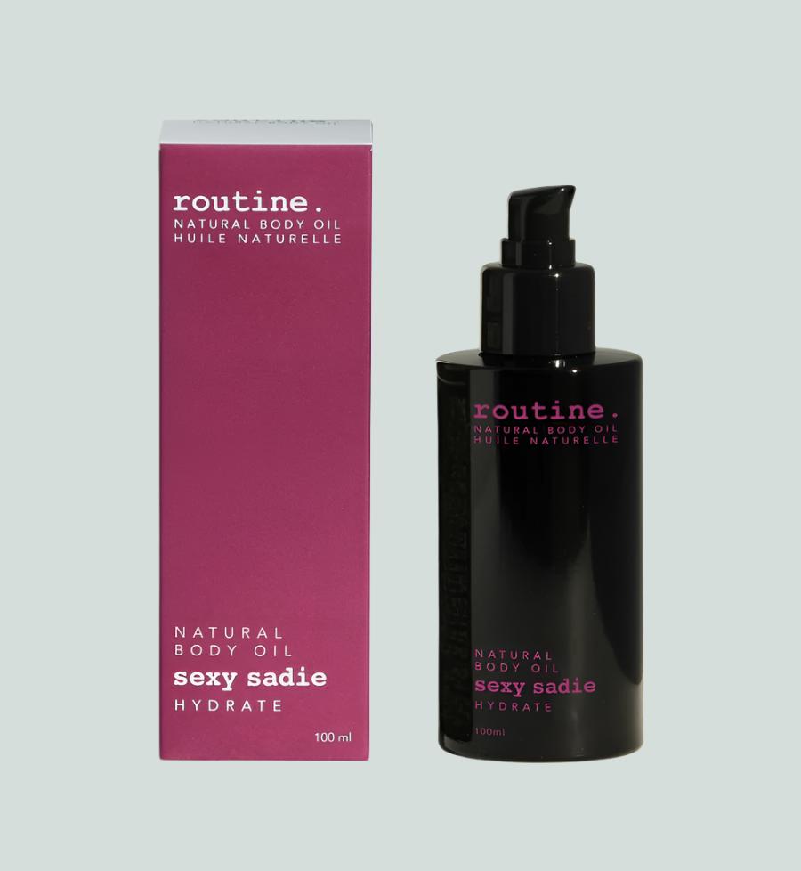 Magenta Box labelled ROUTINE body oil serum - SEXY SADIE - hydrate beside a black sleek bottle with magenta printing on it. Pump top included on the bottle. Clean white background.