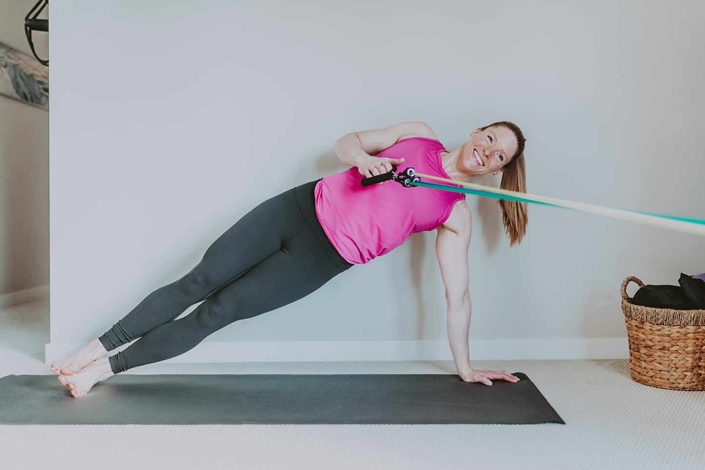 Woman in side plank position - holding body weight and using resistance bands to complete a tow