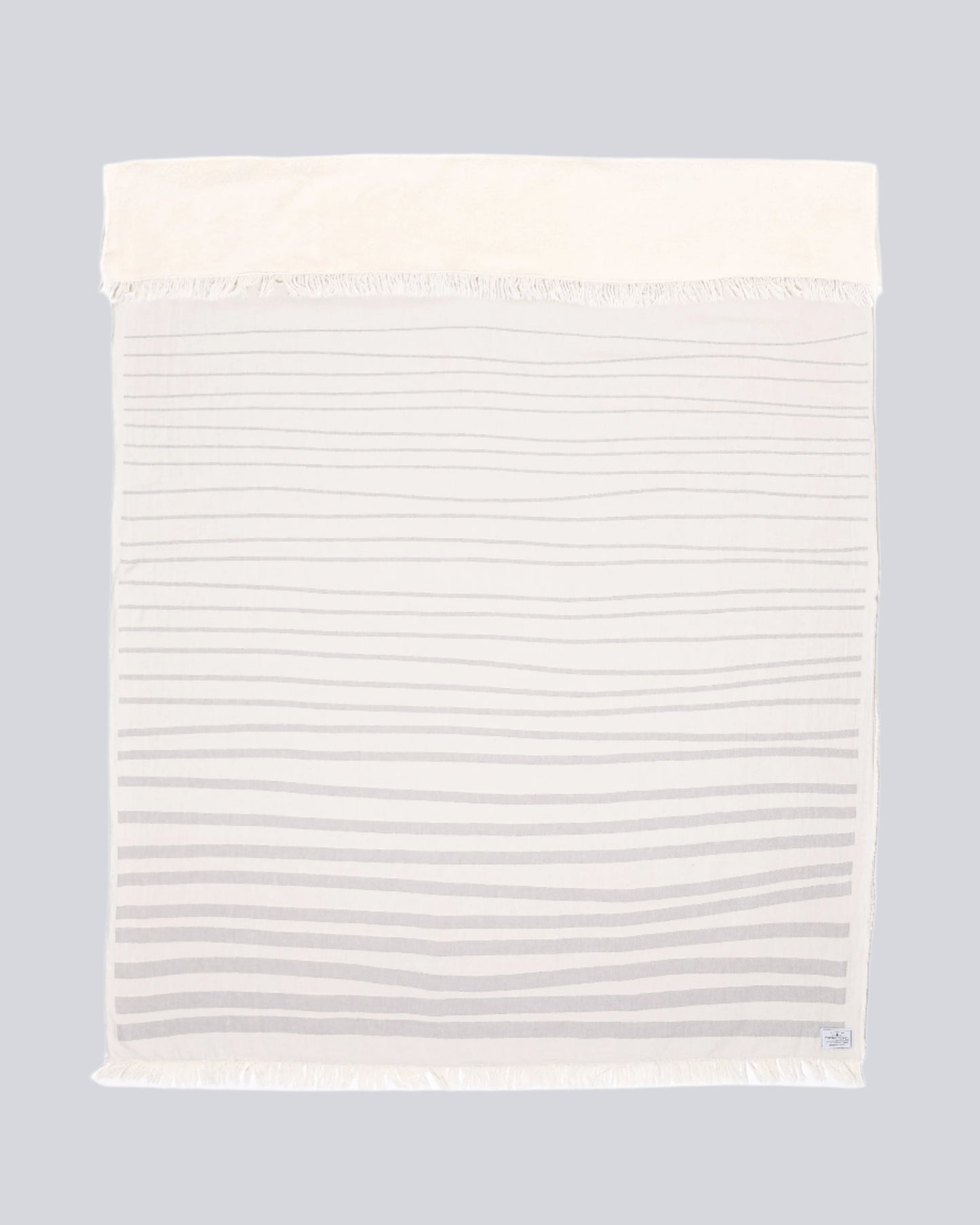 The Rowan Throw from the Tofino Towel Company - In Pewter colour with horizontal ligth grey lines on a white blanket - Turkish Cotton on one side and fleece lined on the other.