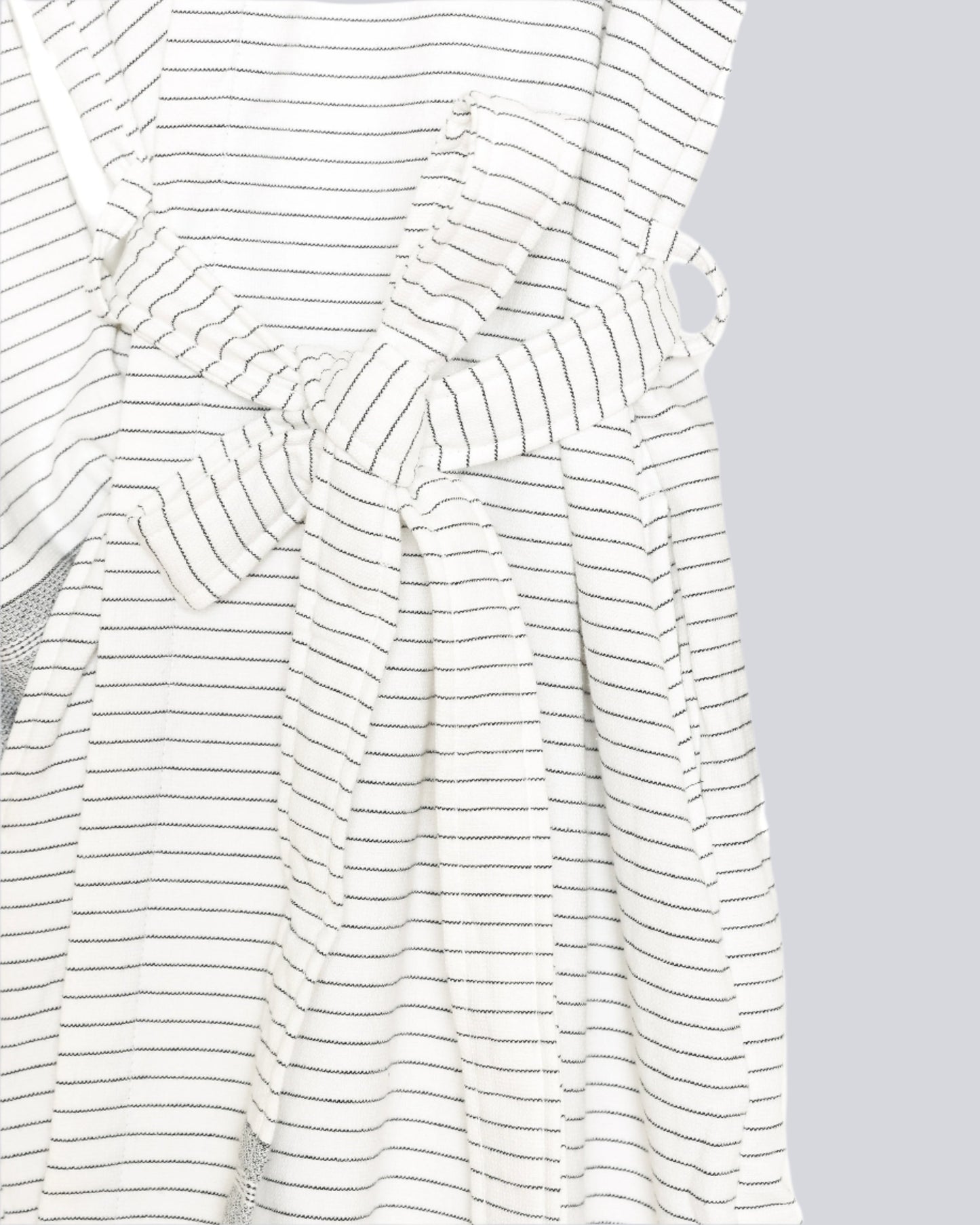 Close up of the waist of The Silas Robe from Tofino Towel Company - off white with black thin horizontal stripes and a hood.  Photographed on a wooden hanger on a white background.