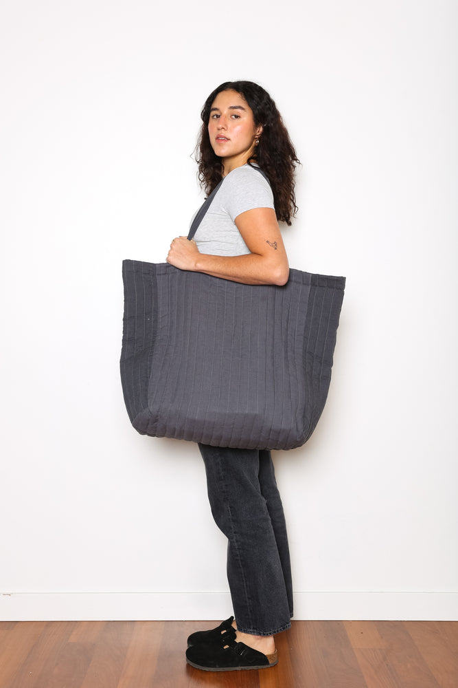 
                  
                    Model showing side shot of Charcoal ESME oversized quilted tote - photographed on a white background 
                  
                